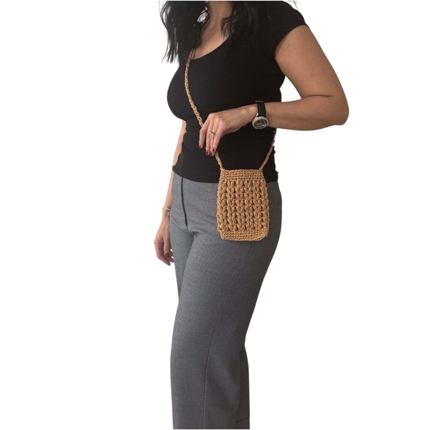 Woman wearing a handmade crochet raffia phone bag in natural straw color, styled as a boho crossbody purse for summer and casual outfits.